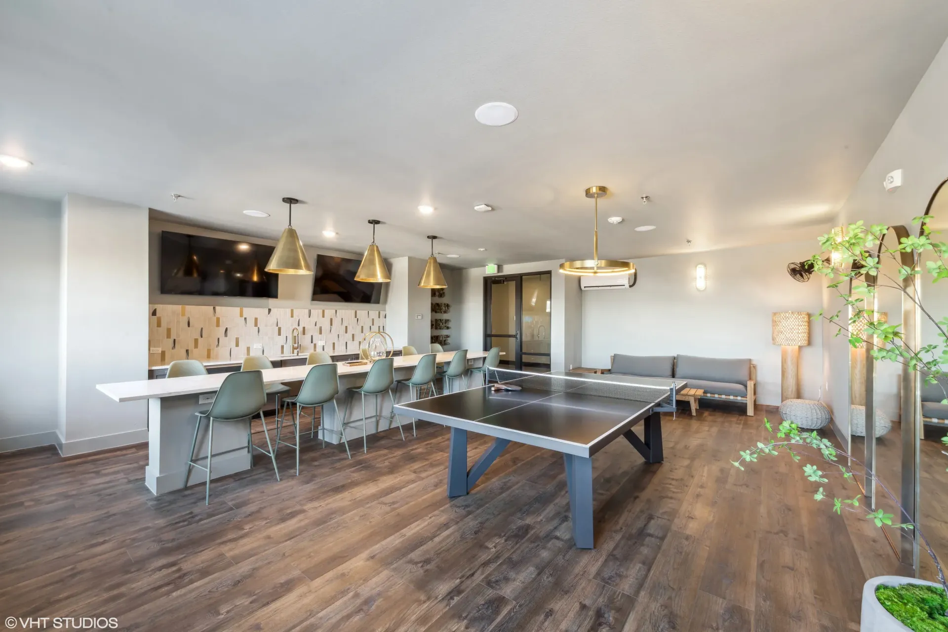 Spacious modern community lounge with bar seating, TVs, and a ping-pong table.