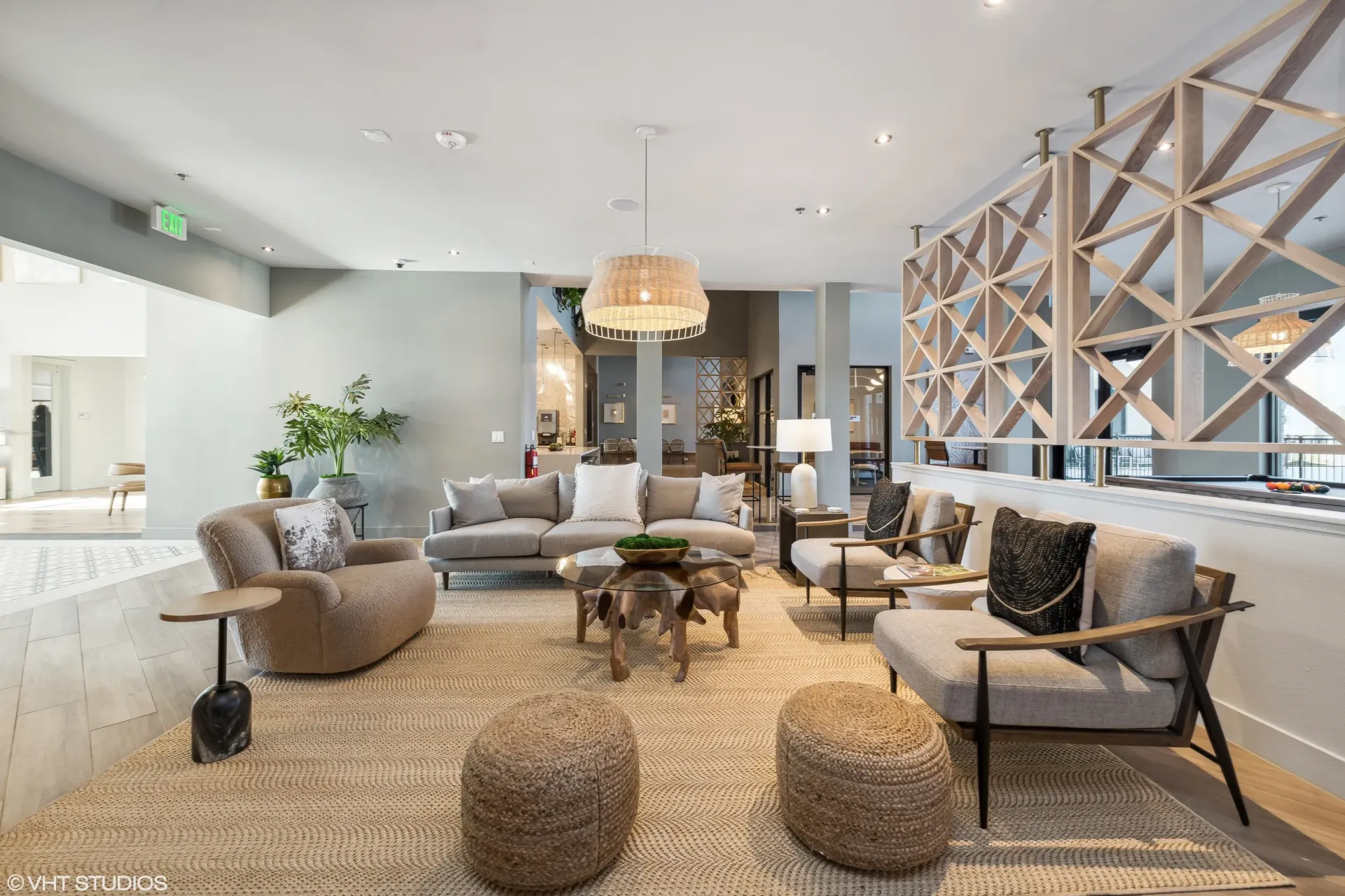 Modern residential lobby with beige seating, plants, and a geometric wooden divider.