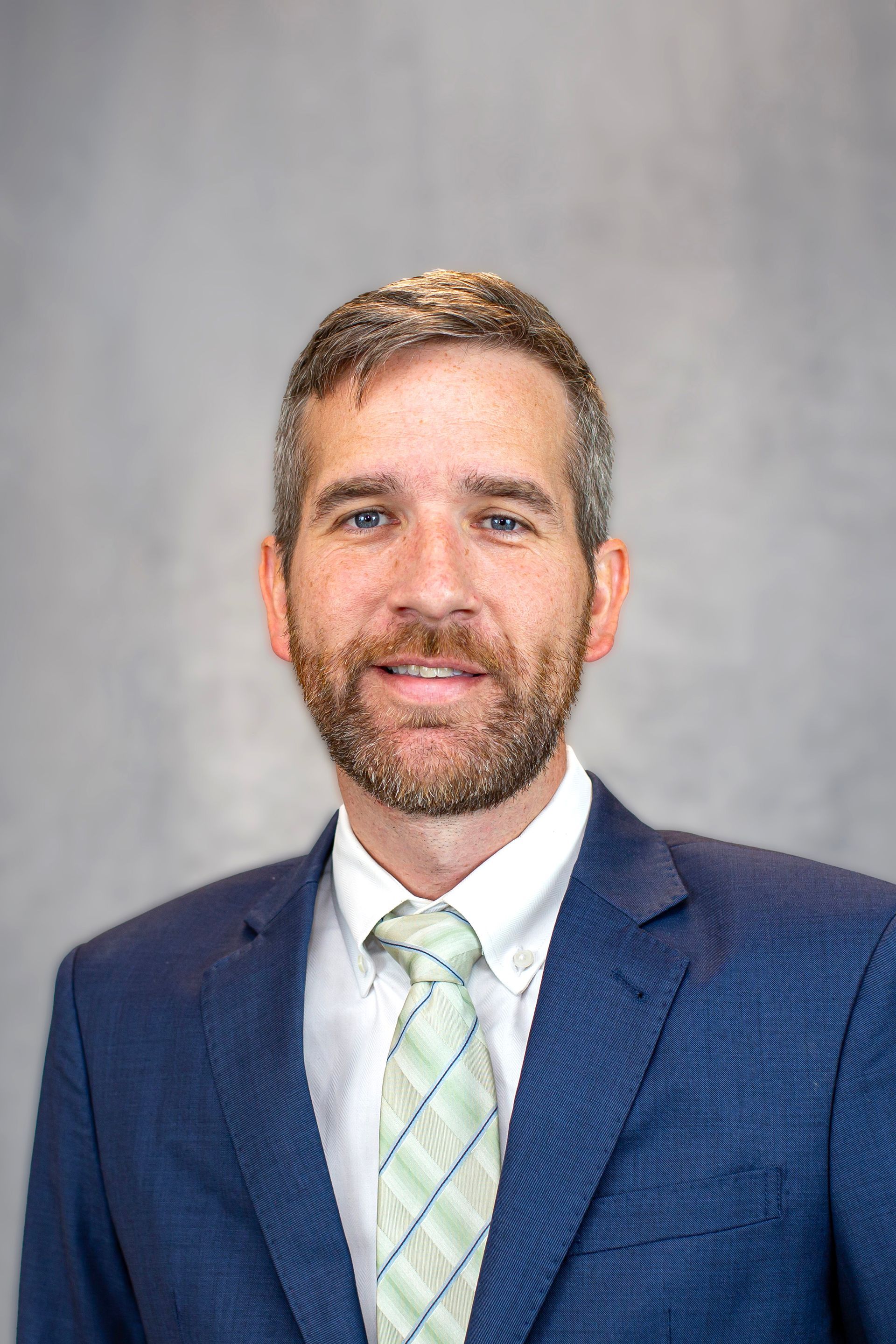 A man in a suit and tie is standing with his arms crossed.