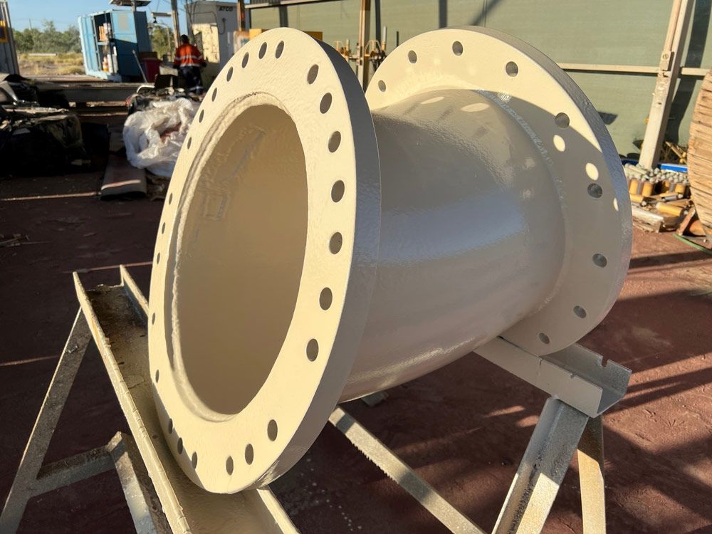 A Large White Pipe Is Sitting On A Wooden Stand After Sandblasting — Procoat QLD in Ryan, QLD