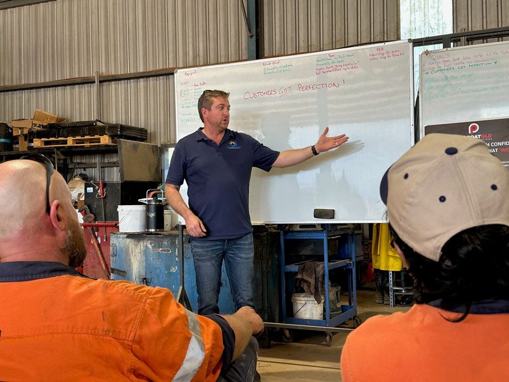 A Man Is Giving A Presentation To A Group Of People In Front Of A Whiteboard — Procoat QLD in Ryan, QLD