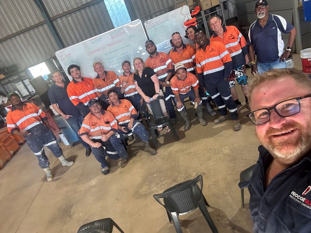 A Group Of Procoat Workers Are Posing For A Picture In A Warehouse — Procoat QLD in Ryan, QLD