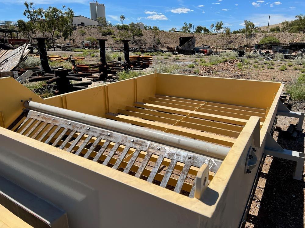 Large Metal Storage Container With Metal Grate on Top in Dirt Field — Procoat QLD in Ryan, QLD