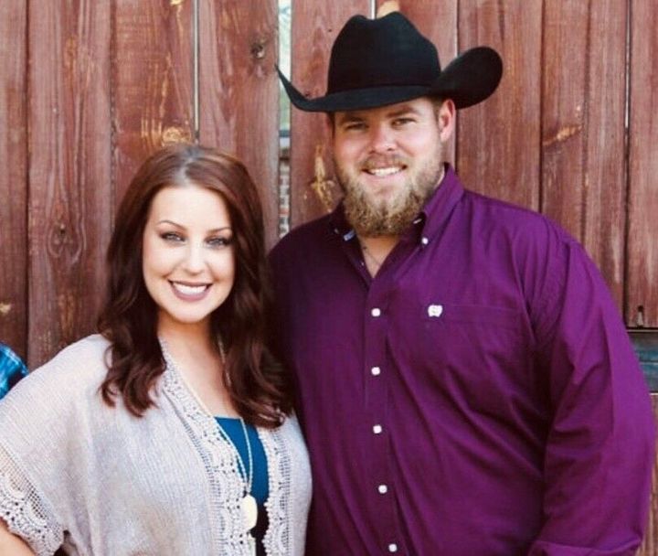 A man in a cowboy hat stands next to a woman in a purple shirt