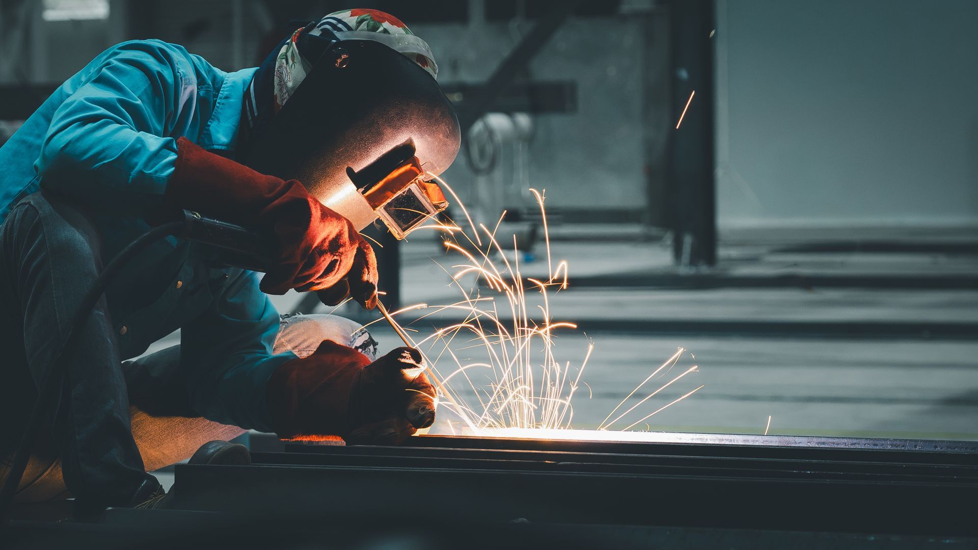Welder wearing protective gear working on metal