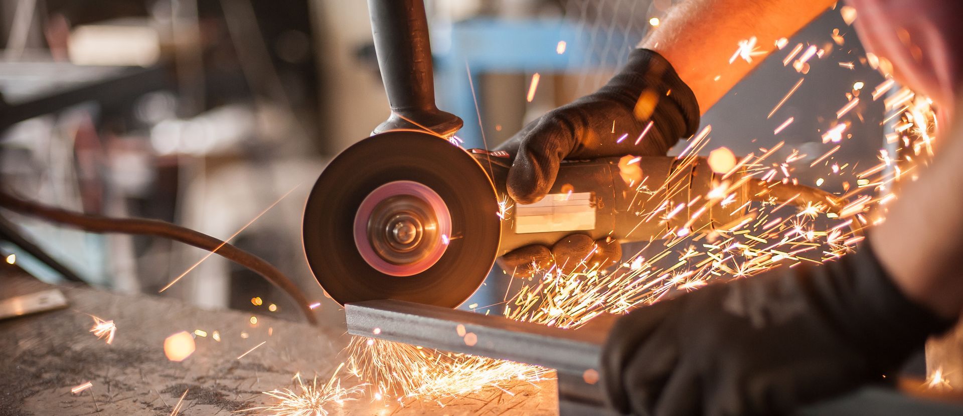 Person using a grinder, creating sparks while working on metal in a workshop