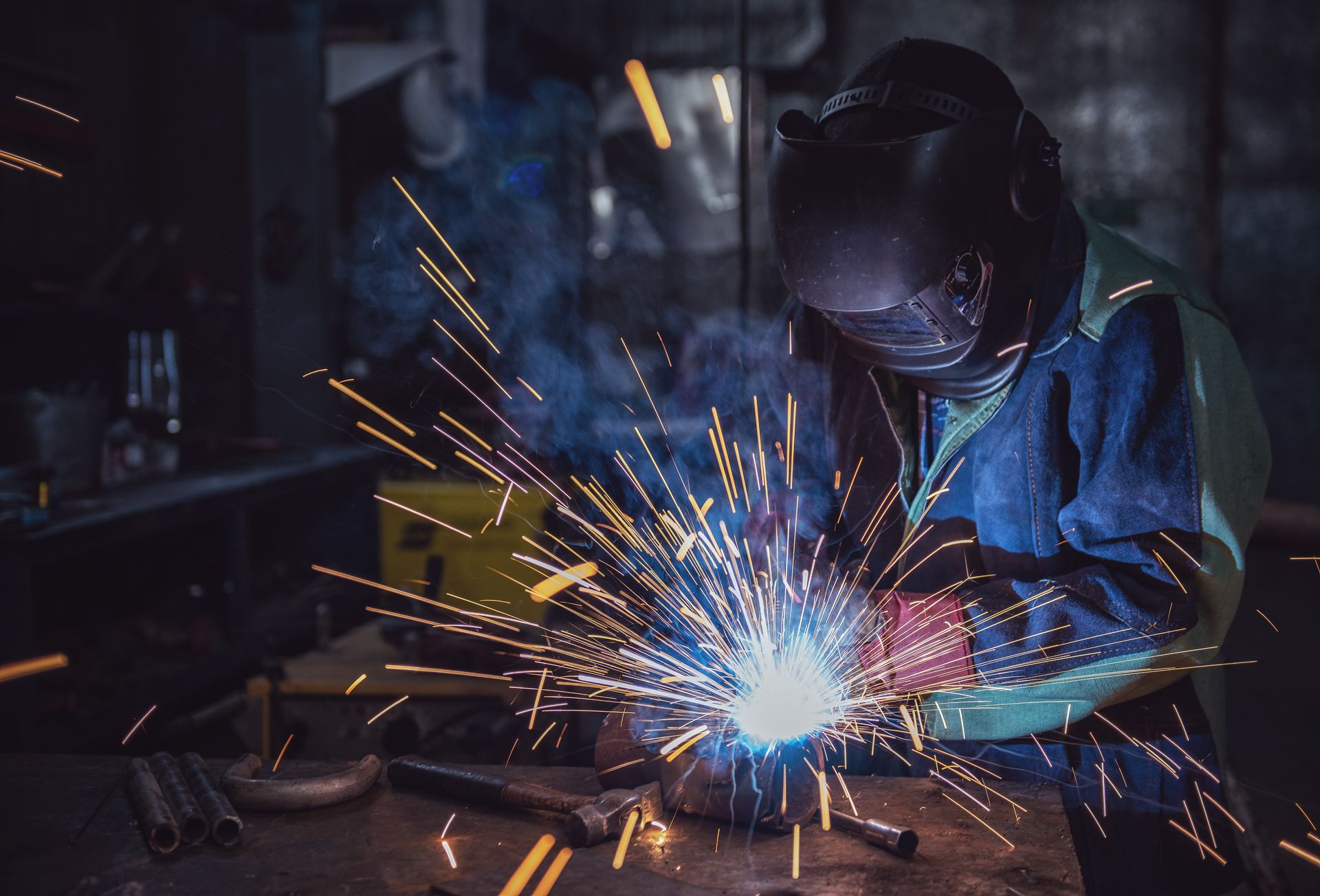 Welder in a workshop, wearing protective gear, welding with bright sparks flying from the work area