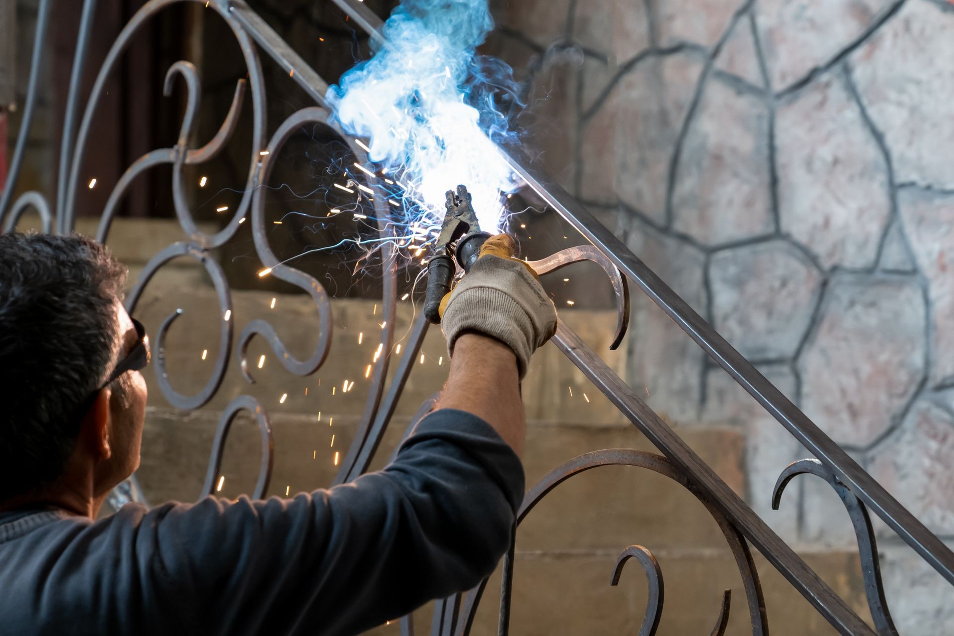 Welder using a torch to repair a black metal railing