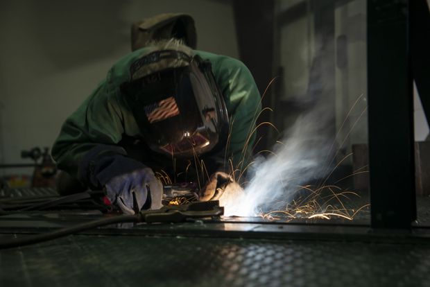 Welder in protective gear, sparks flying, working on metal in a dim setting Welder in protective gear, sparks flying, working on metal in a dim setting