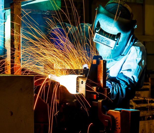 Welder in protective gear, sparks flying, working on metal machinery Welder in protective gear, sparks flying, working on metal machinery