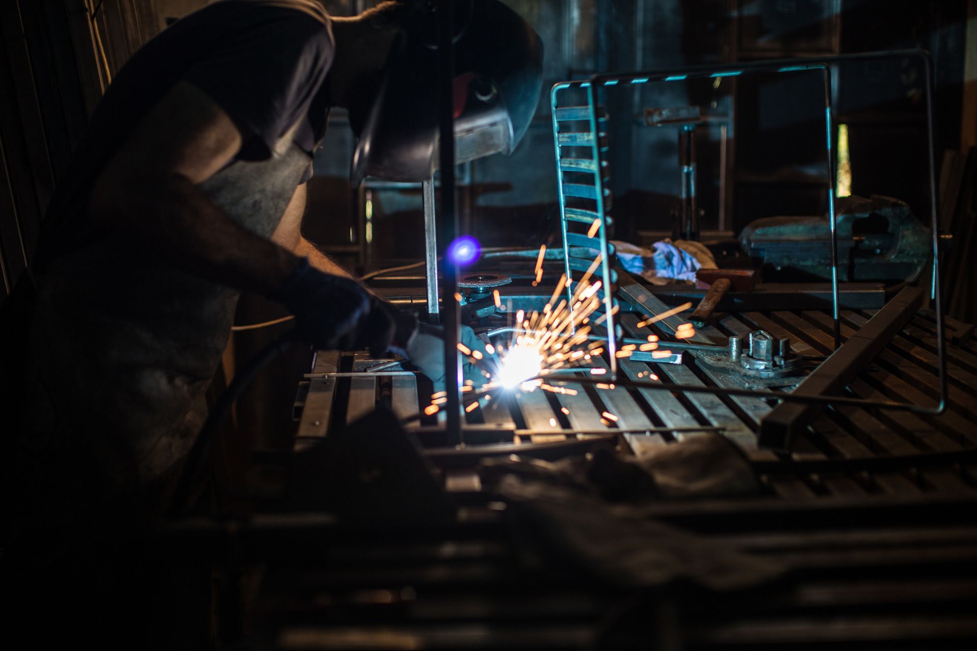 Welder in a workshop, sparks flying as they weld metal