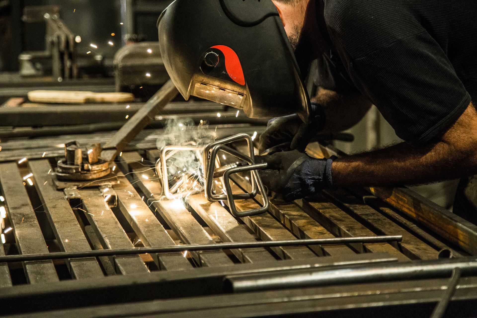 Welder in dark helmet welding metal structure