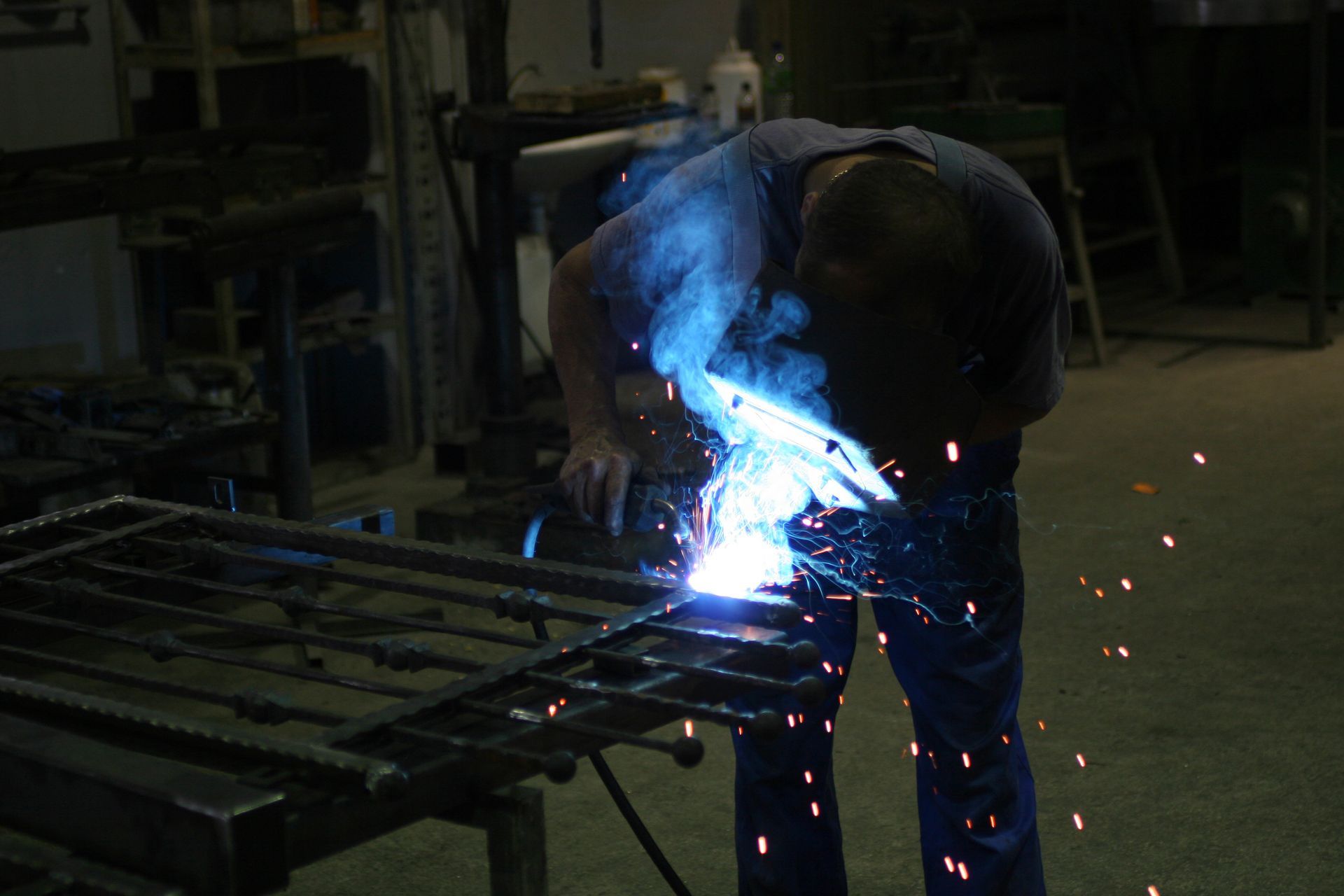 Welder working with a bright blue light on metal in a workshop