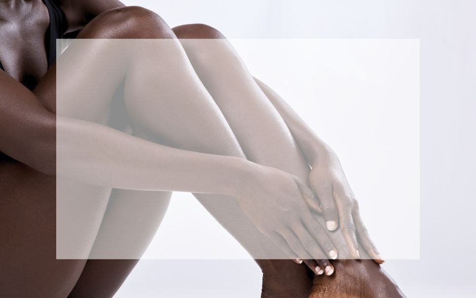 A woman is sitting on the floor with her legs crossed.