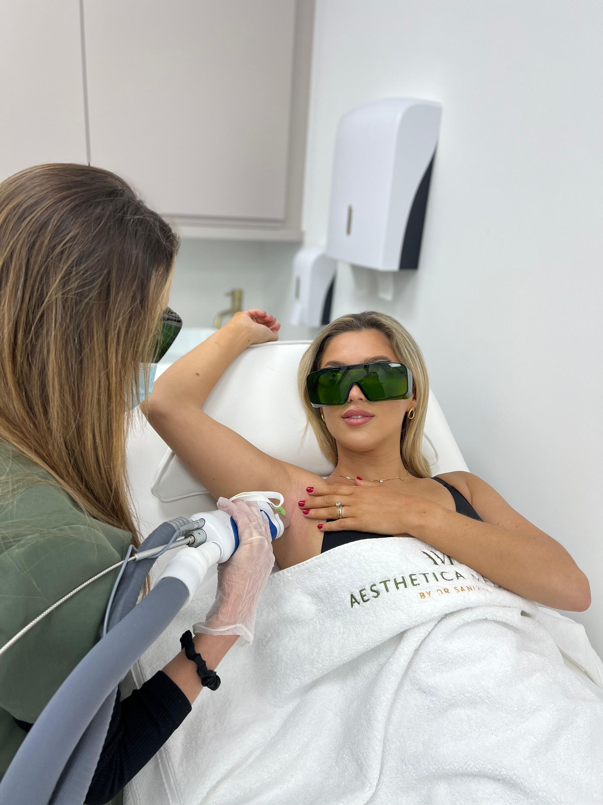A woman is getting a laser hair removal treatment on her armpit.