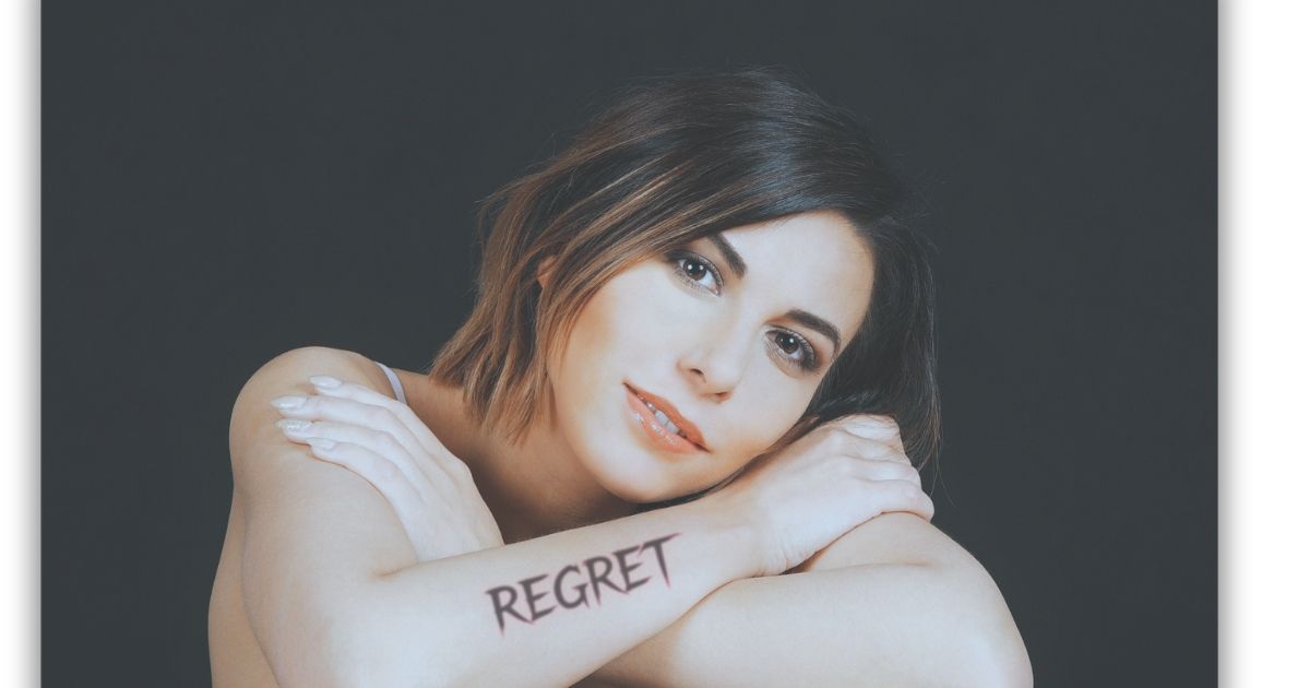 Woman with tatoo on forearm saying regret