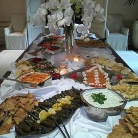 Buffet table with assorted dishes, flowers, and white table settings in a formal dining room