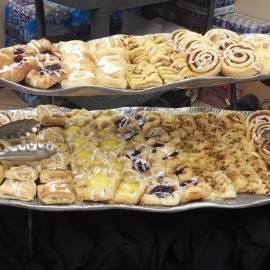 Two trays of assorted iced pastries and cinnamon rolls on a table