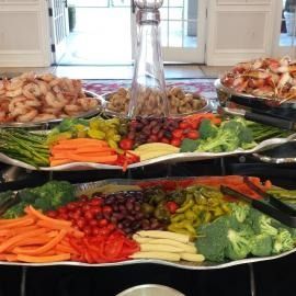 Buffet table with trays of shrimp and colorful raw vegetables arranged on platters