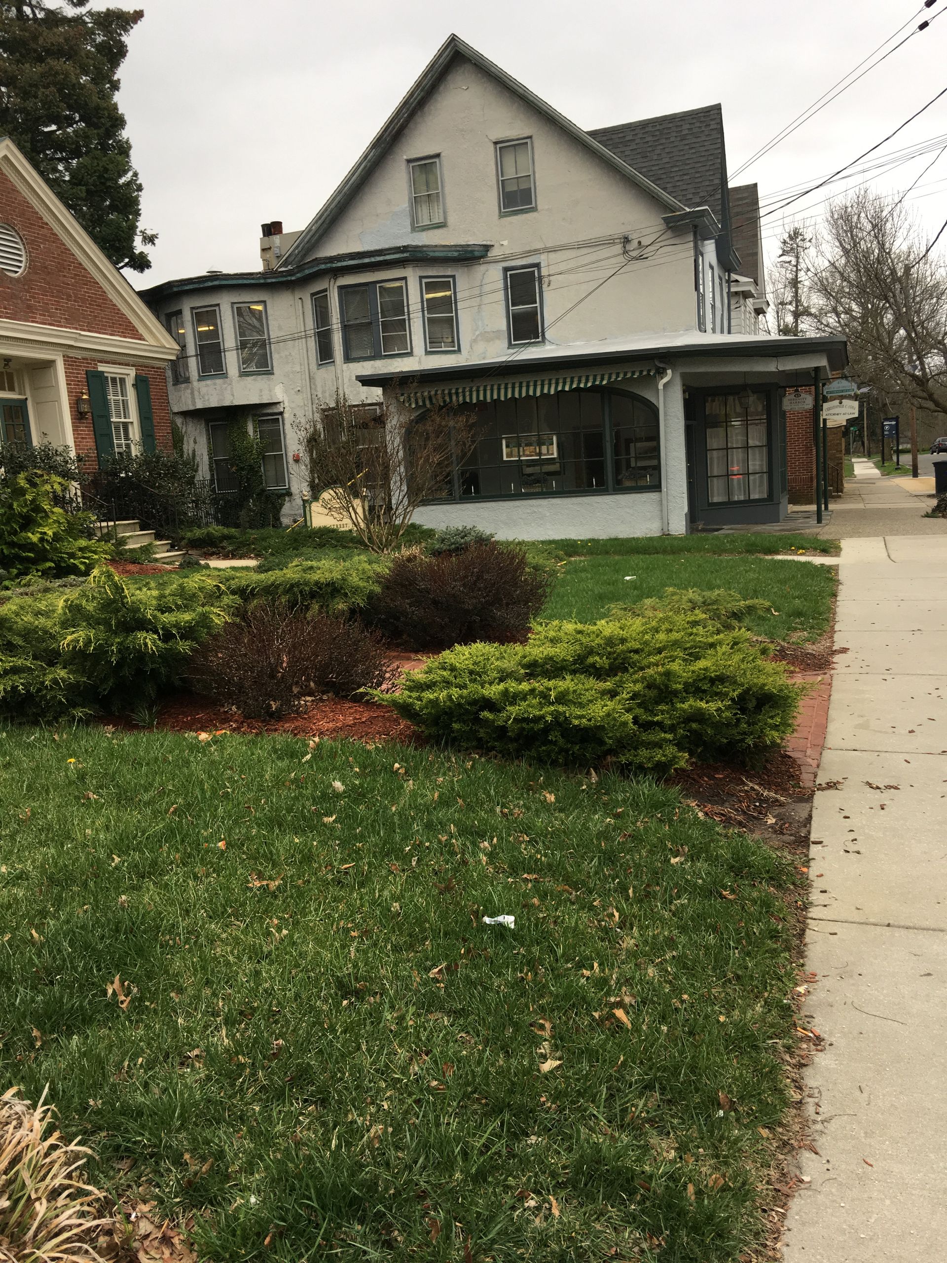 A white house with a black roof is next to a brick house