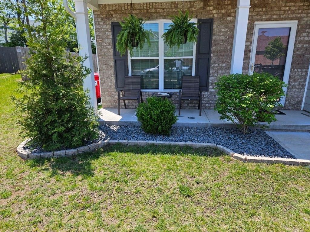 A brick house with a porch and chairs in front of it.