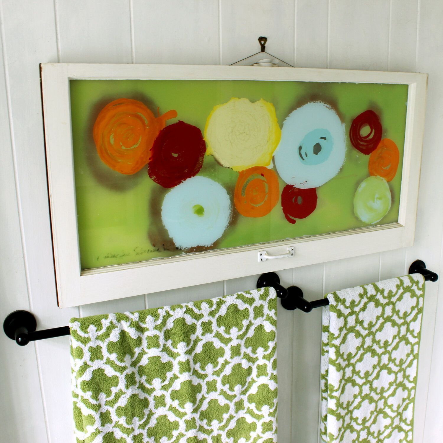 A painting of flowers hangs above a towel rack