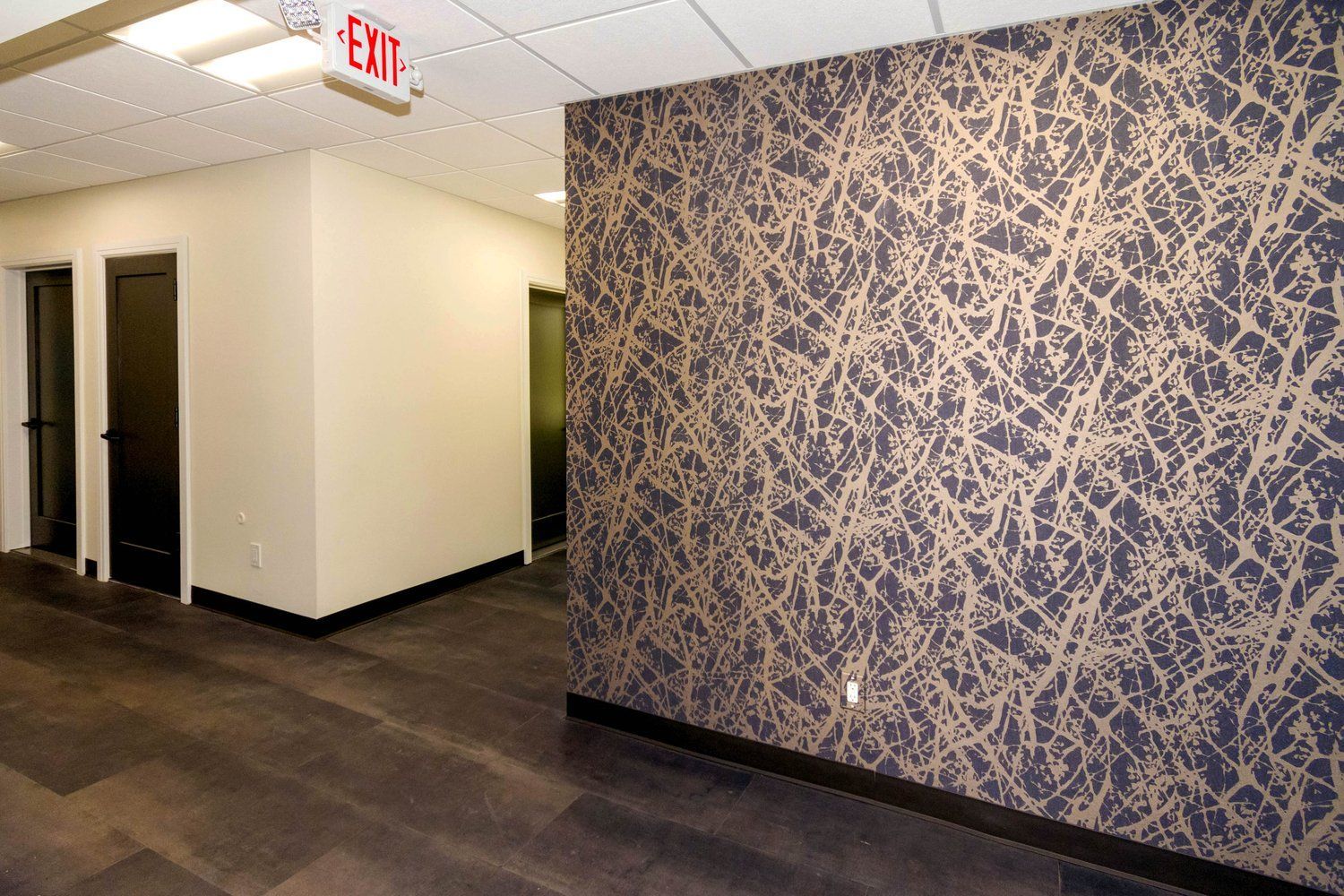 An empty hallway with a red exit sign on the wall.