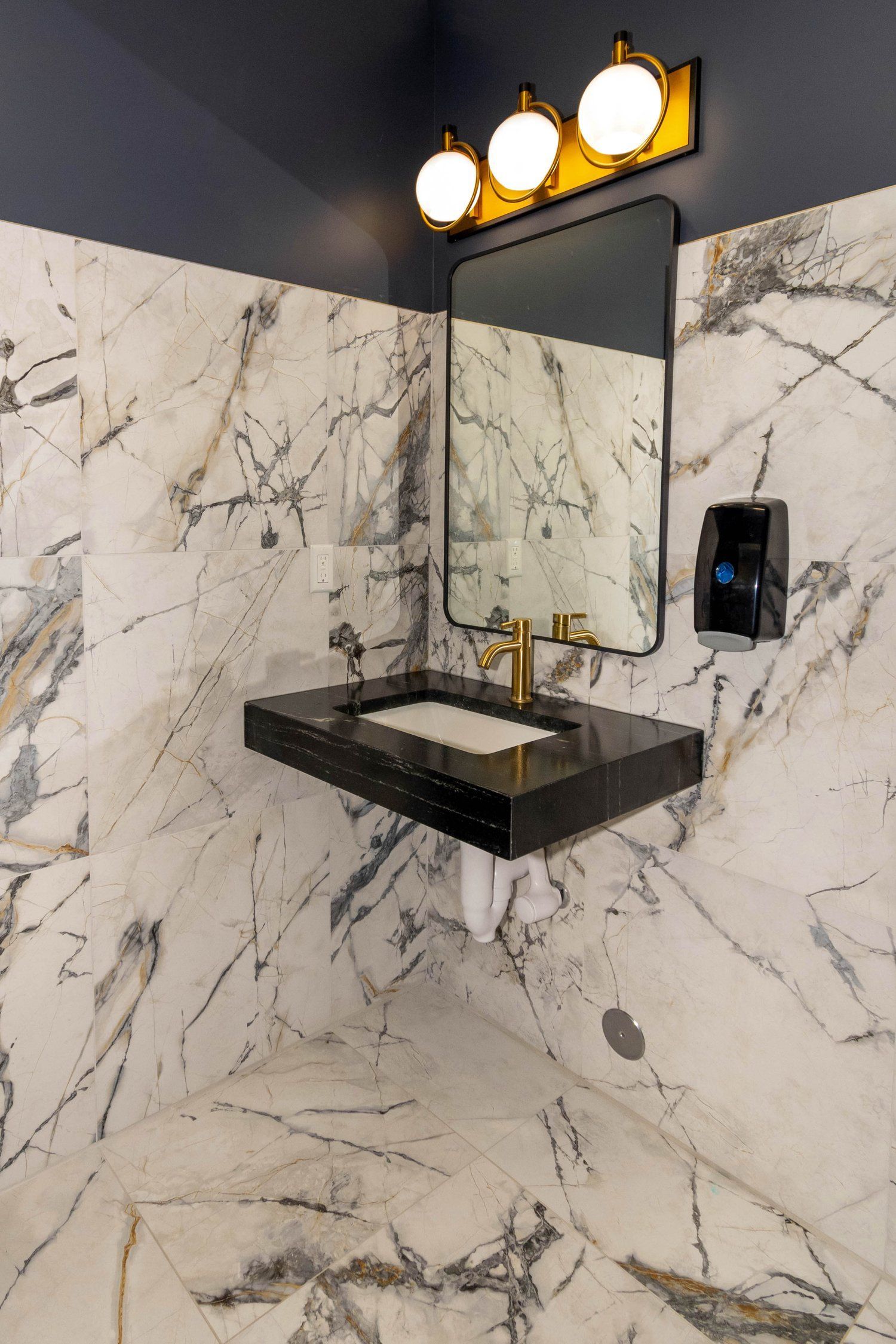 A bathroom with marble walls and a sink and mirror.