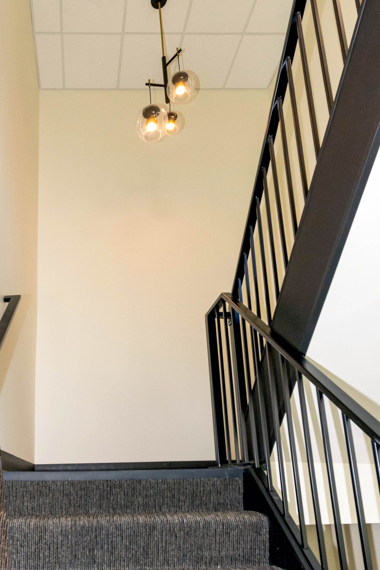 A staircase with a black railing and a light hanging from the ceiling