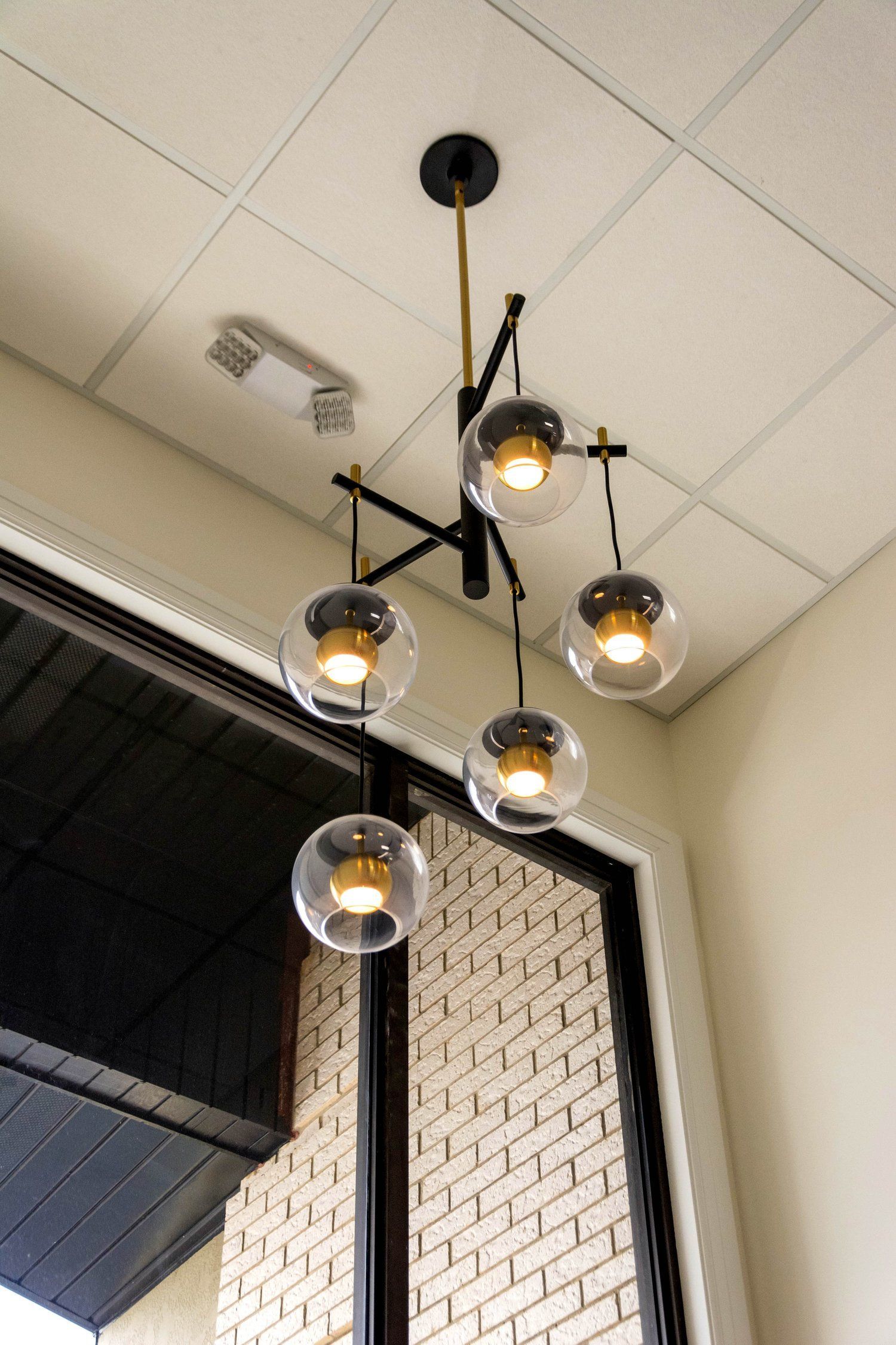 A chandelier is hanging from the ceiling in a room with a brick wall.