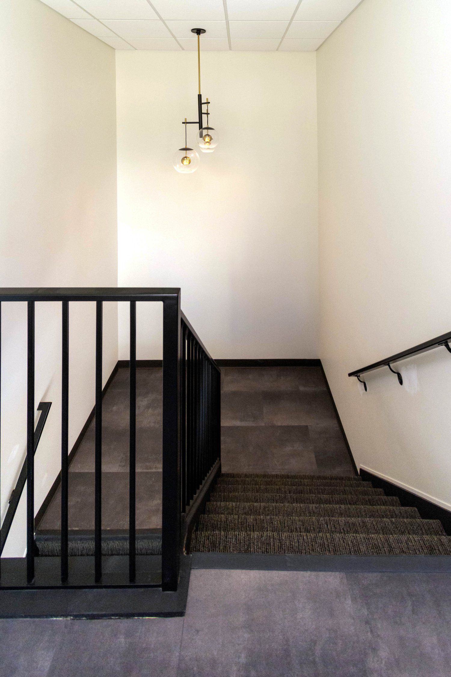 A staircase with a railing and a few lights hanging from the ceiling