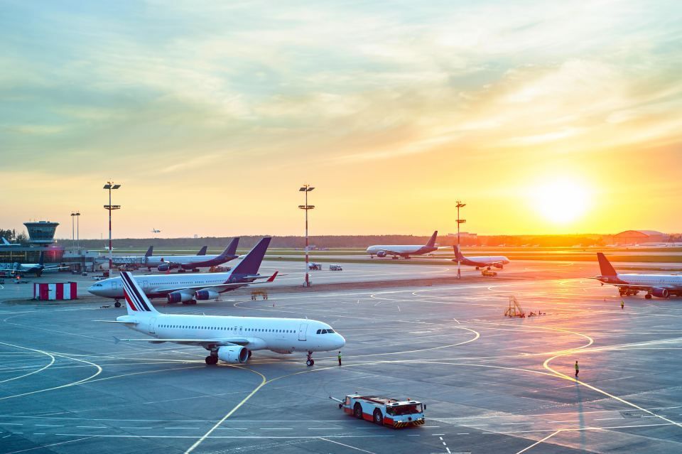 Airplanes parked at an airport, bathed in the golden light of a sunset.