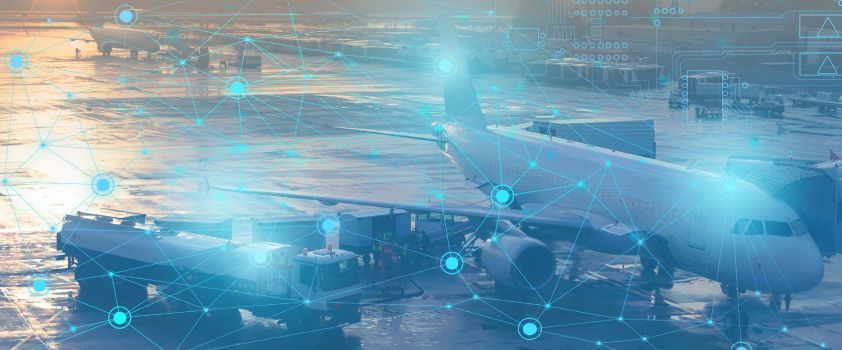 Airplane being serviced at an airport gate; loading cargo, boarding bridge, and other aircraft in the background.