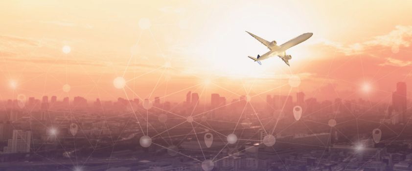 Airplane being serviced at an airport gate; loading cargo, boarding bridge, and other aircraft in the background.