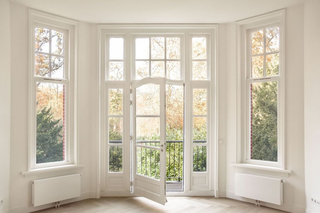 Bright bay window alcove with open French doors and autumn trees outside