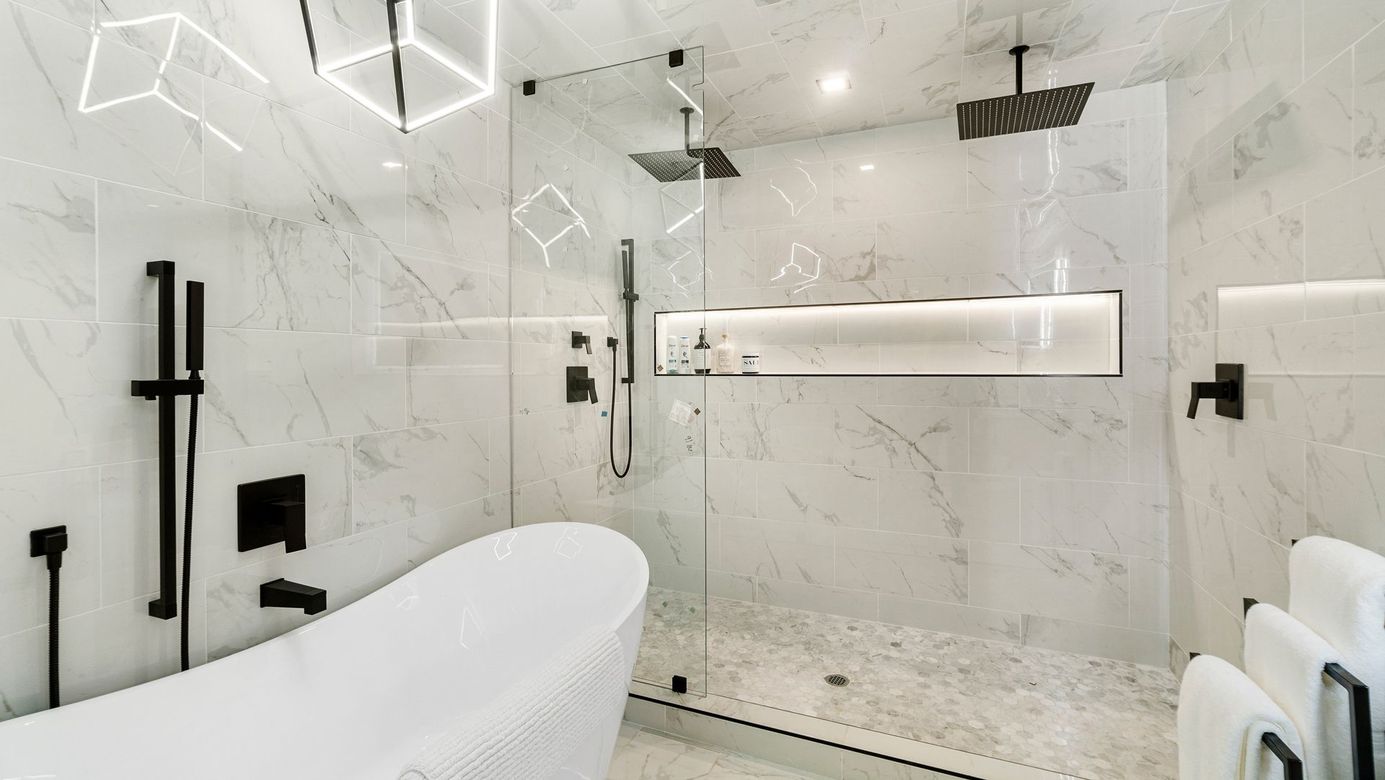 Modern marble bathroom with glass shower, freestanding tub, and black fixtures