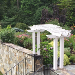 a white pergola is in the middle of a garden
