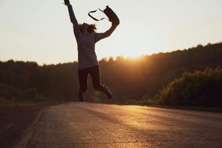 A woman is jumping in the air with her arms in the air.