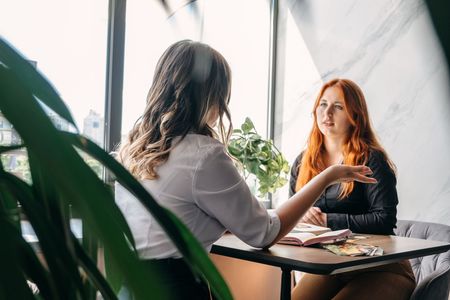 Two women are sitting at a table having a conversation.