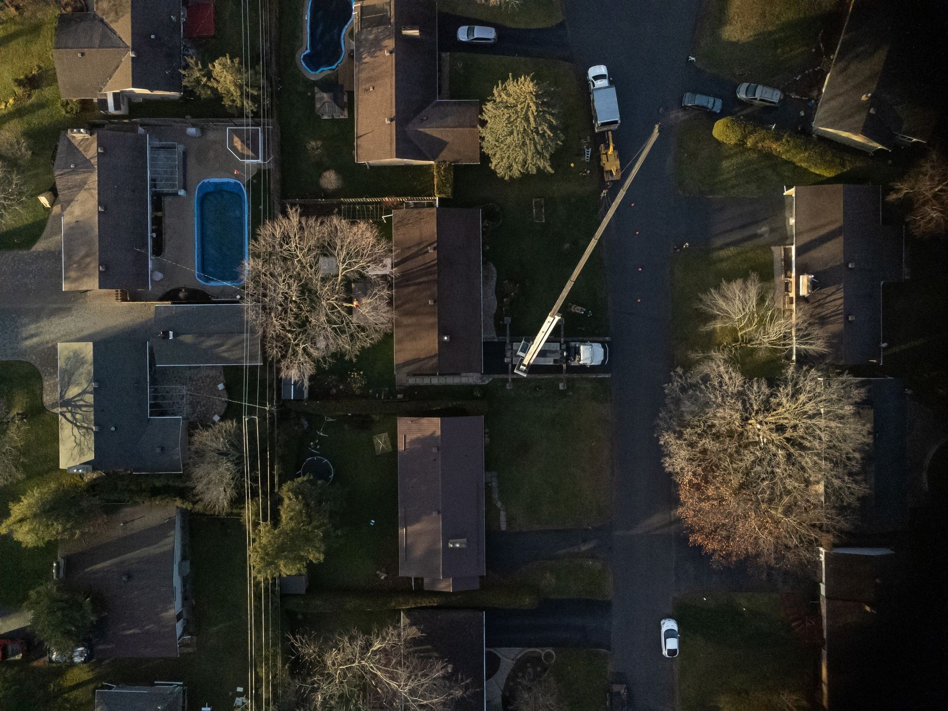 Aerial view of suburban houses with a utility truck and tree work in progress.