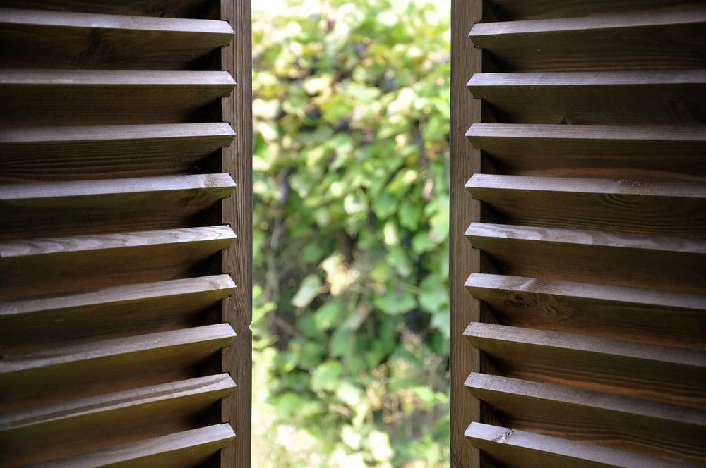 Dark Wooden Shutters And View Of The Garden — Quality Window Coverings in Nowra, NSW