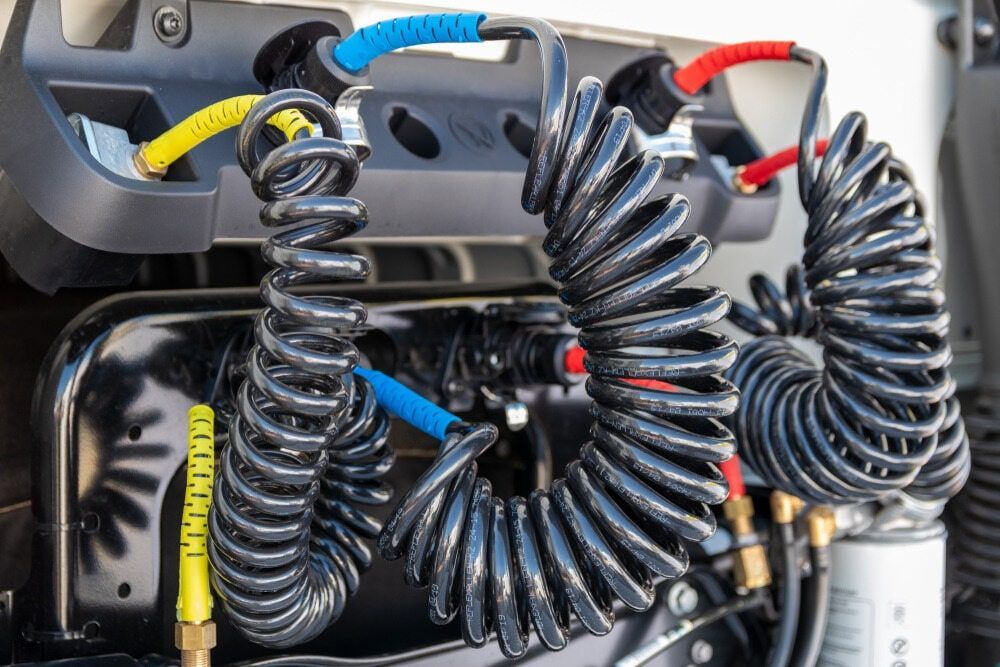 Coiled Air Hoses (Blue, Red, Yellow) Connected to a Black Truck Component — Direct Current Solutions in Mareeba, QLD
