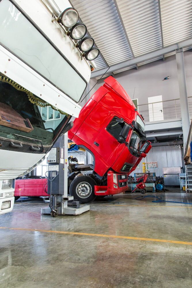 Red Truck Cab Raised in A Repair Shop. Interior View Shows Open Hood, Equipment, and A Lift — Direct Current Solutions in Mareeba, QLD