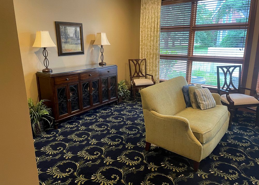 A living room with a couch , chairs , lamps and a window.
