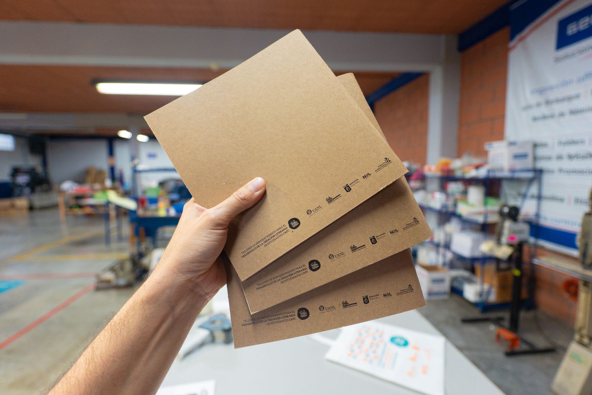 Primer plano de una mano sosteniendo una libreta institucional personalizada, parte del material cor