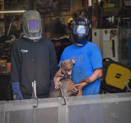 A man wearing a welding helmet holds a brown dog A man wearing a welding helmet holds a brown dog