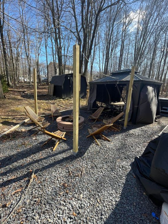 A wooden fence is being built in a gravel area in the woods.