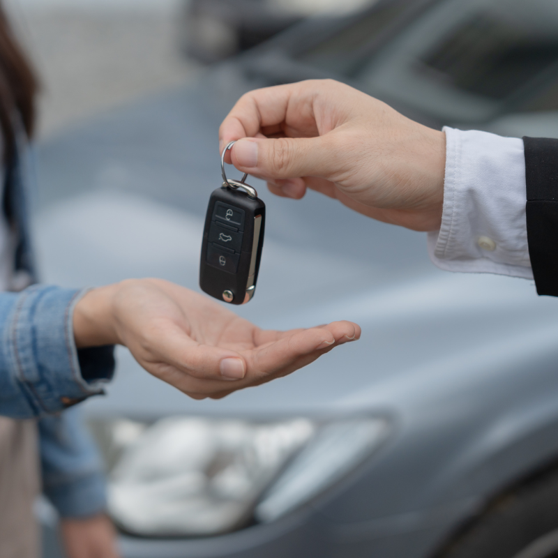 A man is handing a car key to a woman