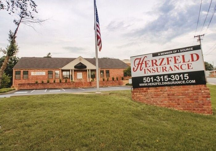 A sign for herzfeld insurance is in front of a brick building
