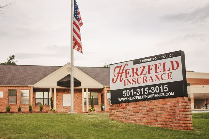 A sign for herzfeld insurance is in front of a brick building.